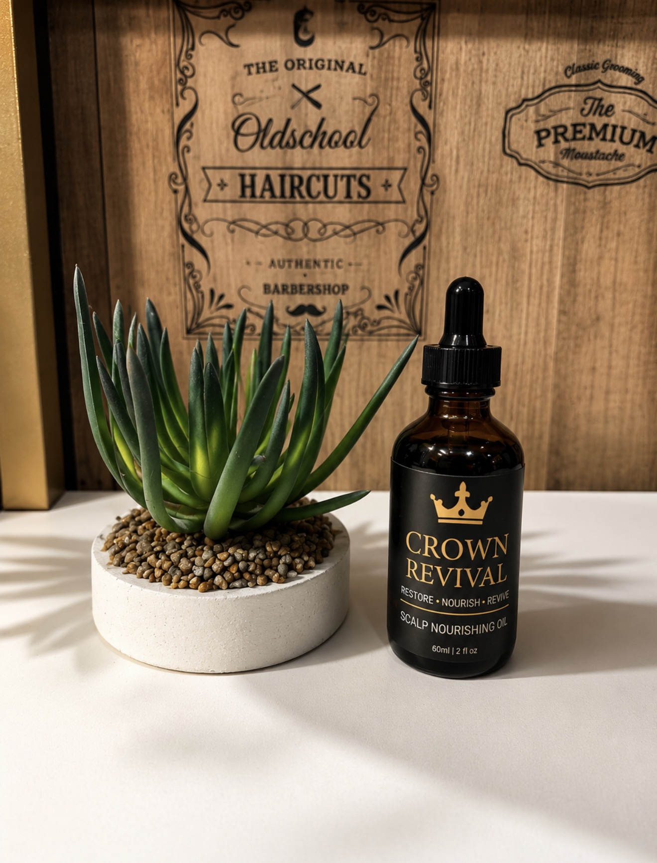Crown Revival Scalp Nourishing Oil, a 60 ml amber glass dropper bottle with a black and gold crown label, on a studio counter